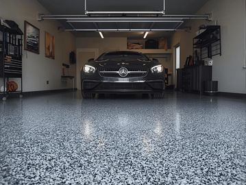 Sleek car on glossy epoxy resin floor in modern home garage, showcasing durable garage flooring.
