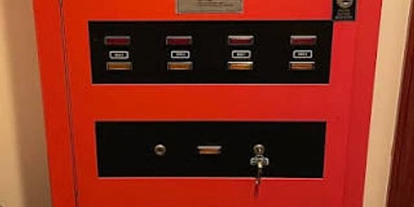 Red vending machine with buttons and a key lock.