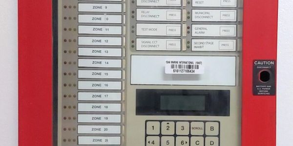 Fire alarm control panel with labeled zones and buttons.