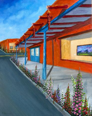 Colorful building with blue pillars and flower-lined sidewalk under a clear sky.