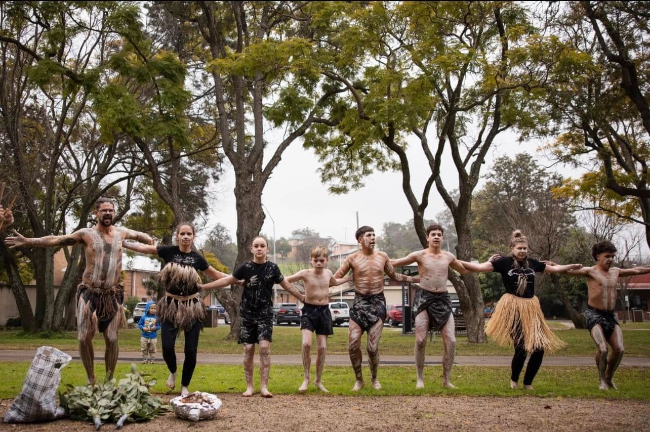 Group of people performing traditional dance outdoors.