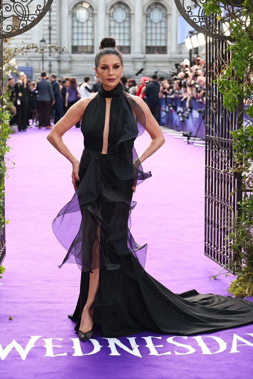 Woman in elegant black dress on purple carpet.