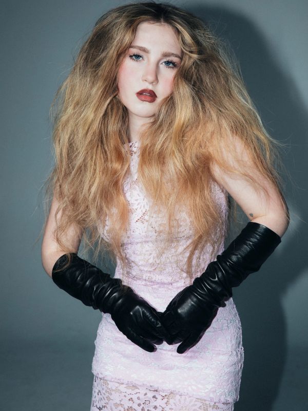 Woman in a delicate pink lace dress and long black gloves.