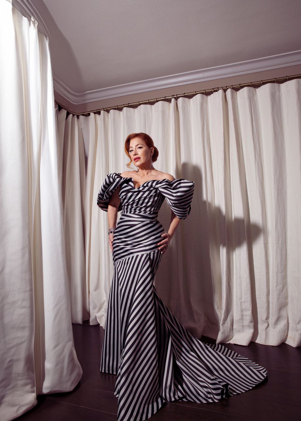 Woman in a dramatic black and white striped gown poses indoors.