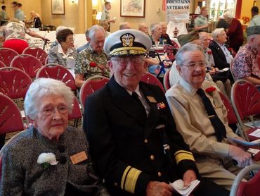 Elderly veterans gathered at a commemorative event.