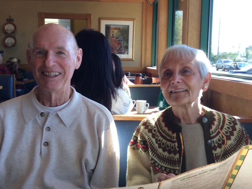 Elderly couple smiling inside a cafe.
