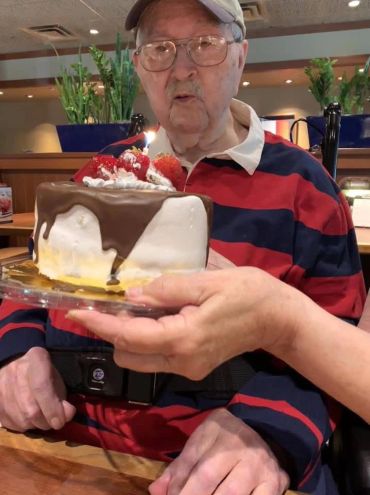Elderly man celebrating birthday with cake.