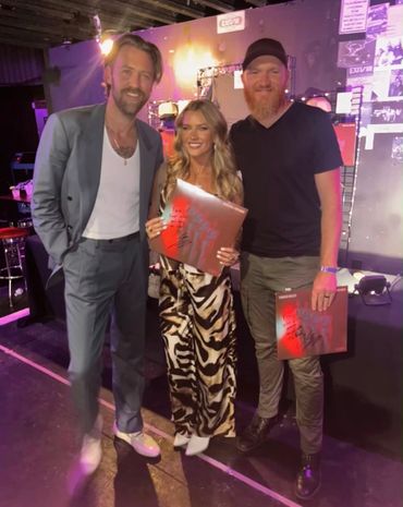 Three people posing with awards at an event venue.