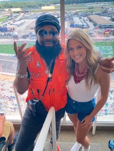 Two friends posing with a racetrack in the background.