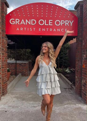 Woman posing happily under the Grand Ole Opry artist entrance sign.