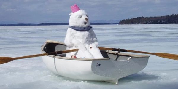 A snowman in a rowboat on a frozen lake
