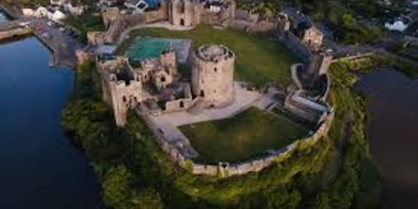 Aerial view of a historic stone castle surrounded by water and greenery.