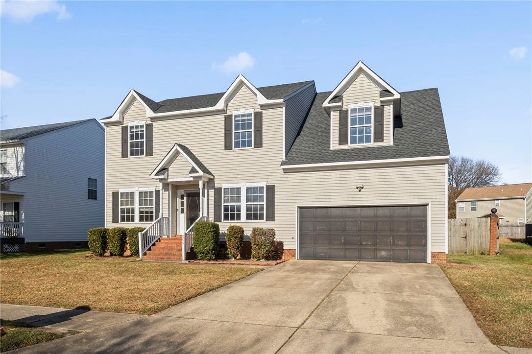 Two-story suburban house with beige siding and a large driveway.