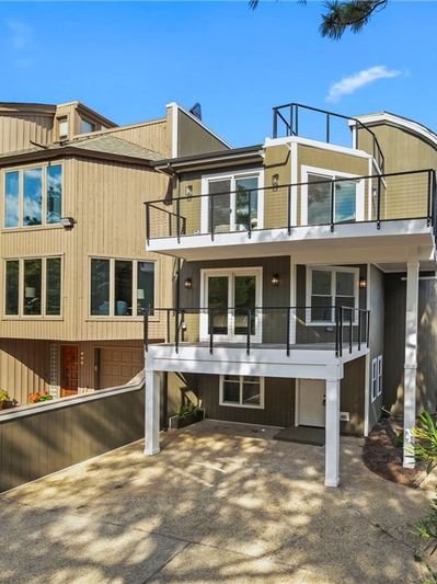Modern multi-level house with balconies and a driveway.
