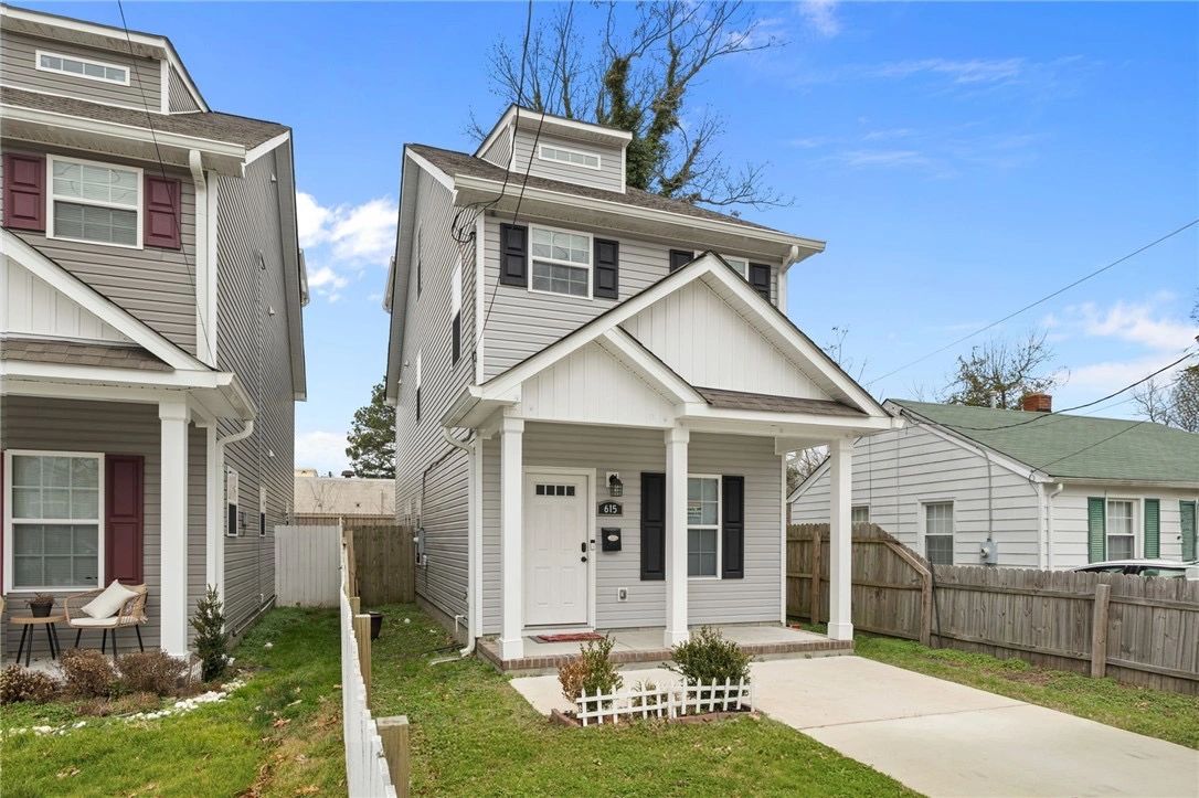 A gray two-story house with a white porch and driveway.