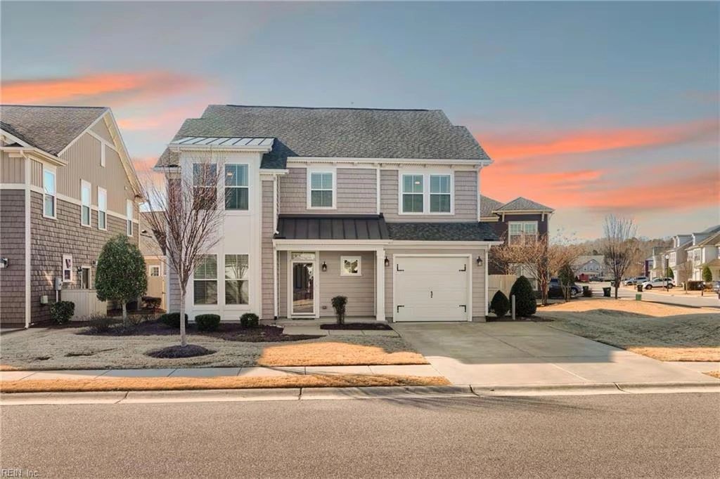 Modern two-story house with a garage under a colorful sunset sky.