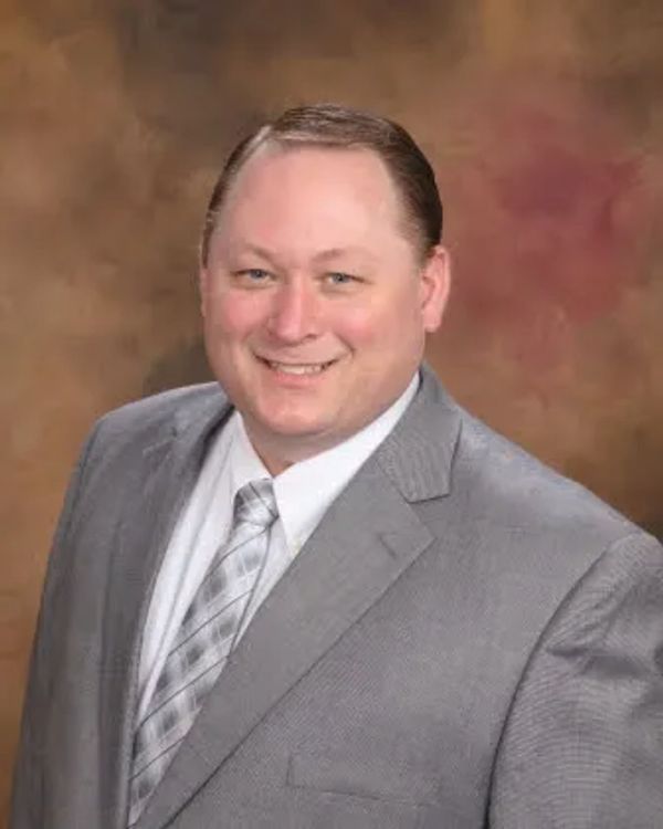 Smiling man in a gray suit and tie.