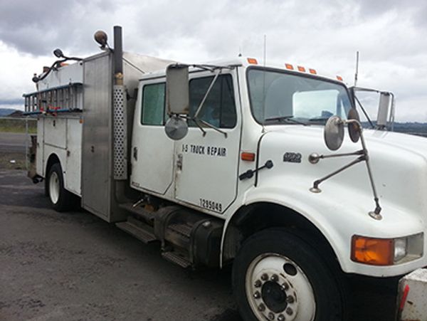 Technician working on a big rig trailer at roadside on Interstate 5 corridor