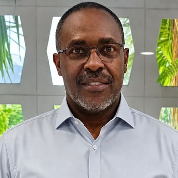 A middle-aged man wearing glasses and a light blue shirt.