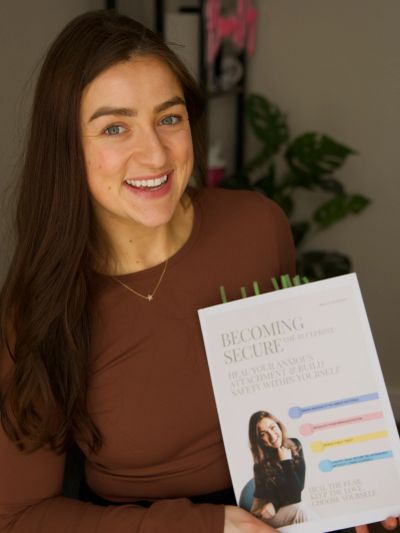 Woman smiling holding a book titled 'Becoming Secure.'