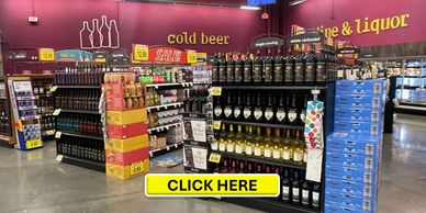Store aisle featuring cold beer and liquor with sale signs and various bottles on display.
