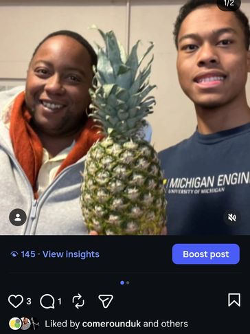 Two people smiling with a large pineapple.