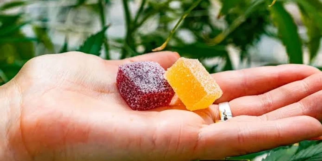 Two sugar-coated gummy candies on a hand.