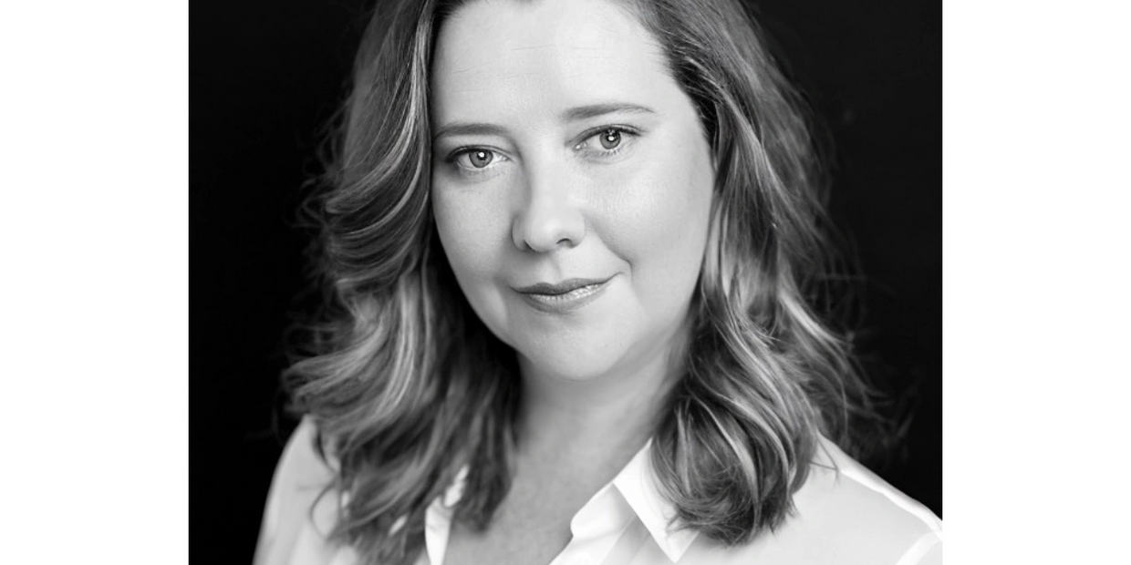 A black and white photo of Fiona Simpson. Her wavy hair sits at her shoulders and she is wearing a w