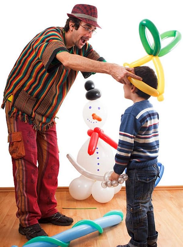 a man putting a twisted balloon on the head of a kid 