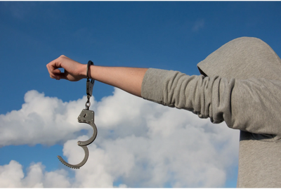 Image of a person's arm with one handcuff on showing addiction