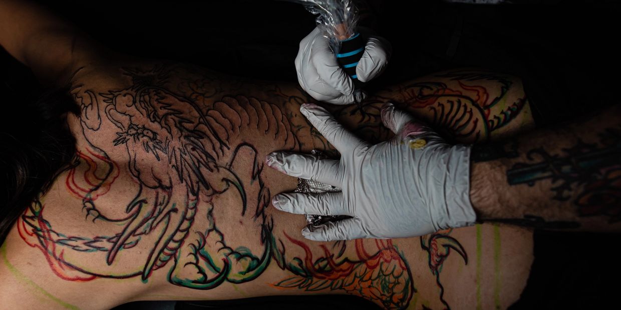 Tattoo artist working on a large dragon back tattoo.