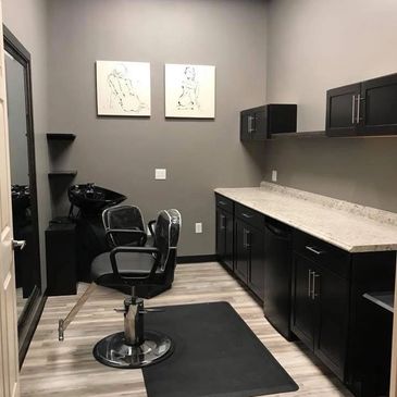 Modern hair salon with black styling chairs and sleek cabinetry.