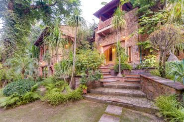 Stone house with lush garden and steps.