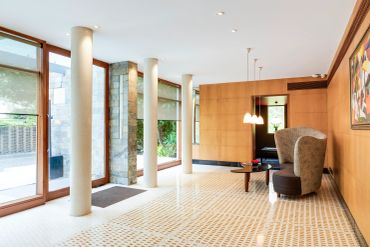 Modern lobby with large windows, columns, and seating area.