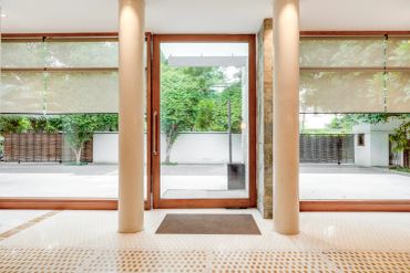 Bright entrance with glass doors and large windows showing greenery outside.