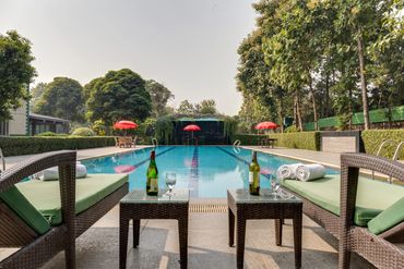 Relaxing poolside setup with chairs and wine bottles.