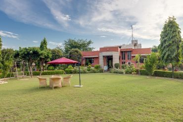 Large garden with outdoor seating and a brick house.