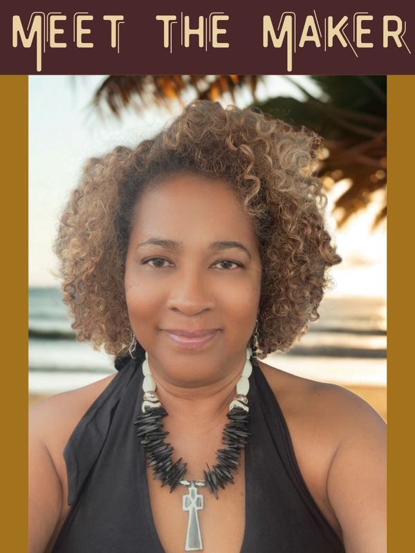 Portrait of a smiling woman with curly hair and a distinctive necklace at the beach.