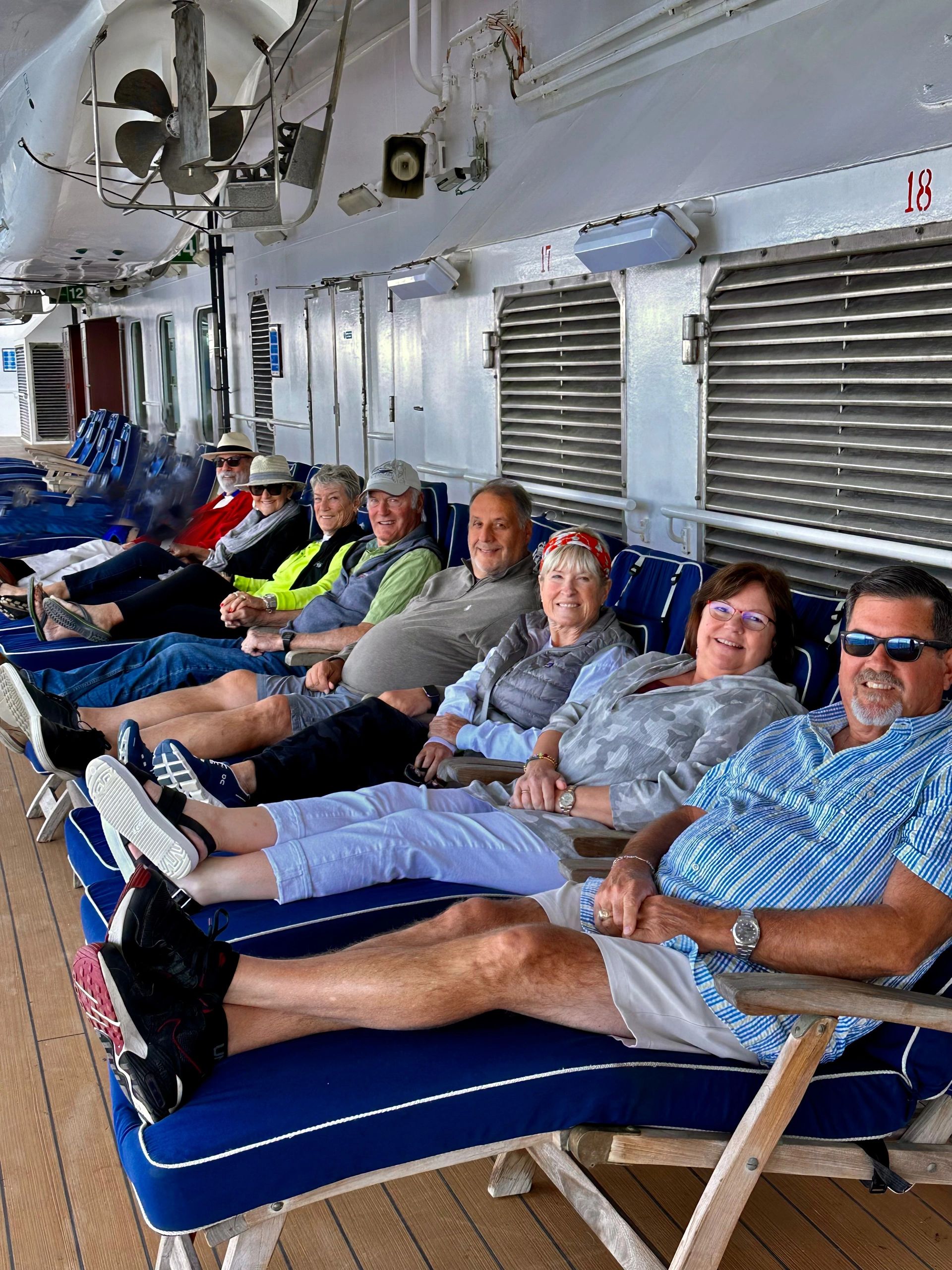 Group of older adults relaxing on lounge chairs on a ship deck.