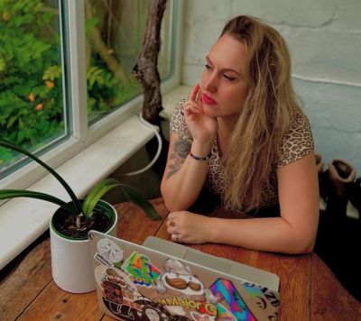 Woman lost in thought by a window with her laptop.