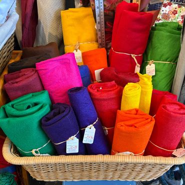 Colorful fabric rolls neatly arranged in a basket at a fabric store.