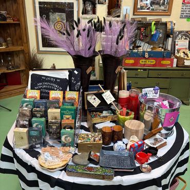 A table with tarot cards, crystals, candles, and decorative items in a vintage shop.