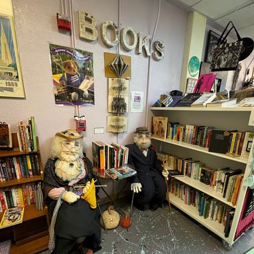 Quirky bookstore corner with elderly mannequins, books, and artistic decor.