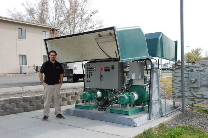 Engineered Water Flow Management Systems And Solutions Technician In Front Of Equipment