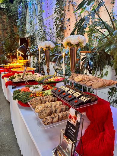 Elegant dessert and appetizer buffet table with flowers and candles.