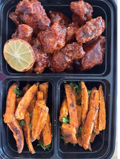 Spicy chicken wings with lemon and two portions of sweet potato fries.