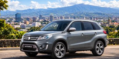 Silver Suzuki Vitara parked with city and mountain backdrop.