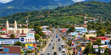Busy road in a vibrant town nestled in green hills.