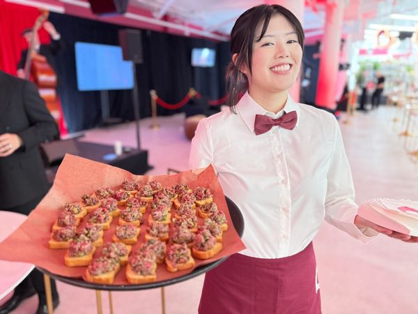Smiling server holding a tray of appetizers at an event.