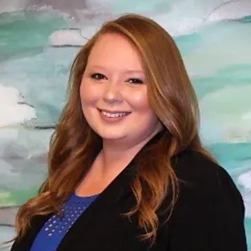 Smiling woman with long hair in a black blazer and blue top.